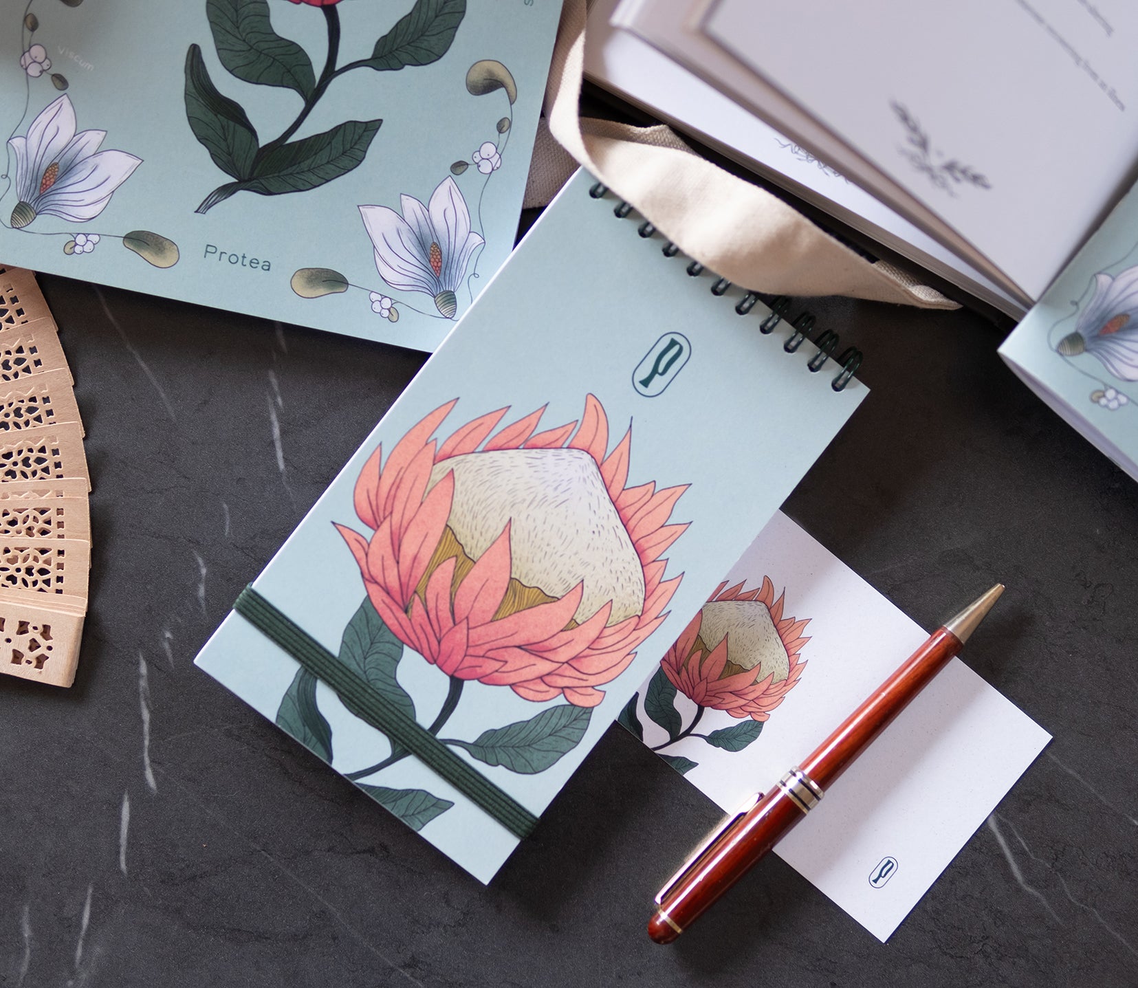 Colombo Protea di Piperita Paper: taccuino tascabile 10x17 cm, pagine bianche, copertina con stampa floreale e spirale, perfetto per appunti e idee creative.